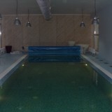 Переливной бассейн в частном доме, оснащенный плавающим покрывалом для предотвращения испарения воды с поверхности