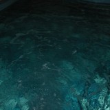 Вода в чаше стационарного скиммерного бассейна, очищенная специальными химическими реагентами и фильтром, для безопасного плавания всей семьей