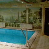 Вид частного скиммерного бассейна с декоративной отделкой из мозаики и настенным панно